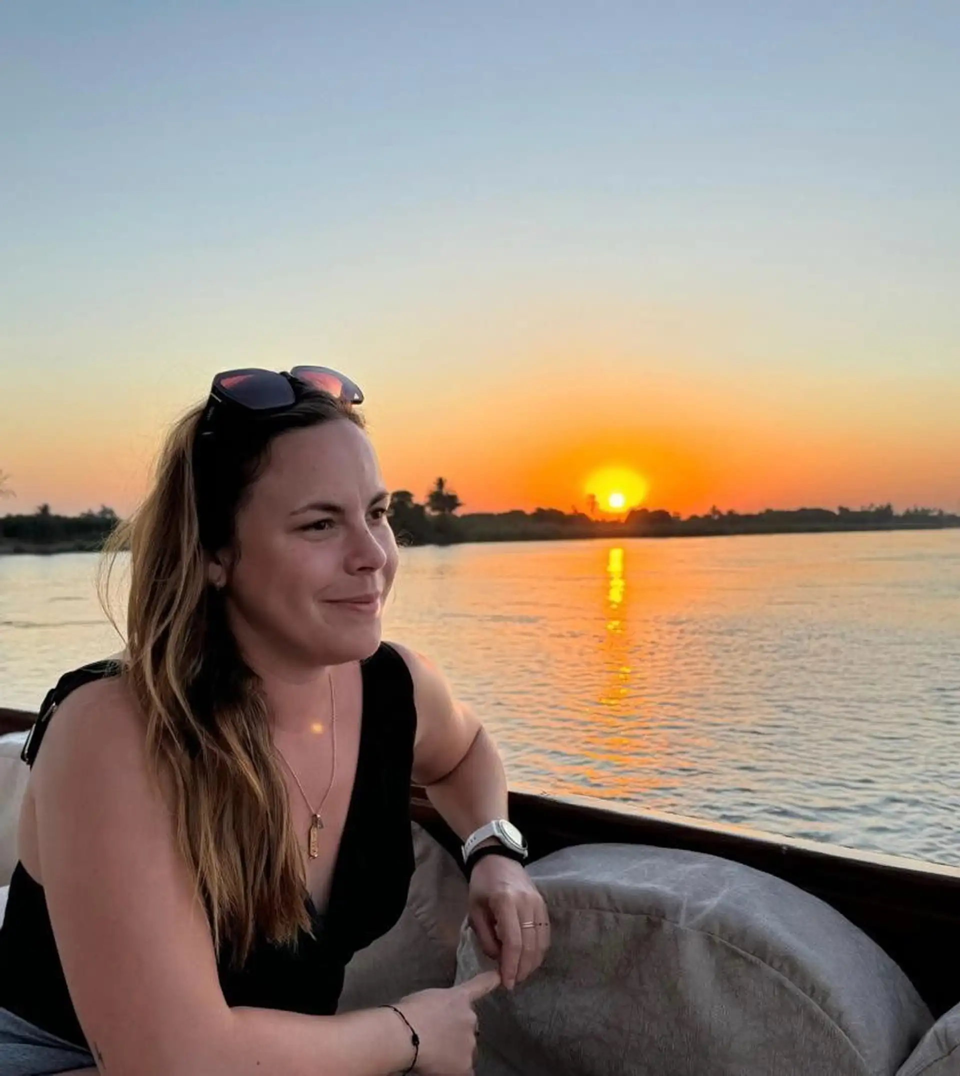 Portrait de Sonia, conseillère en voyage chez Shanti Travel, posant de profil devant un magnifique coucher de soleil sur l'horizon.