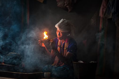 Travel in Asia - A woman of the Karen hill tribe in Thailand smoking a traditional tobacco pipe