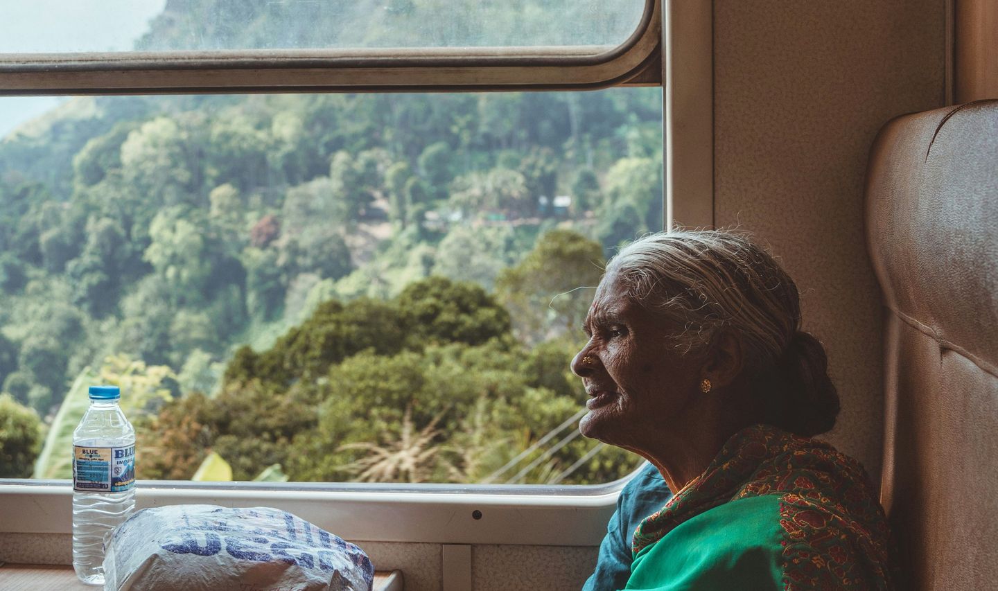Travel in Asia - An elderly woman wearing a traditional sari sitting in a window seat on a train in Sri Lanka