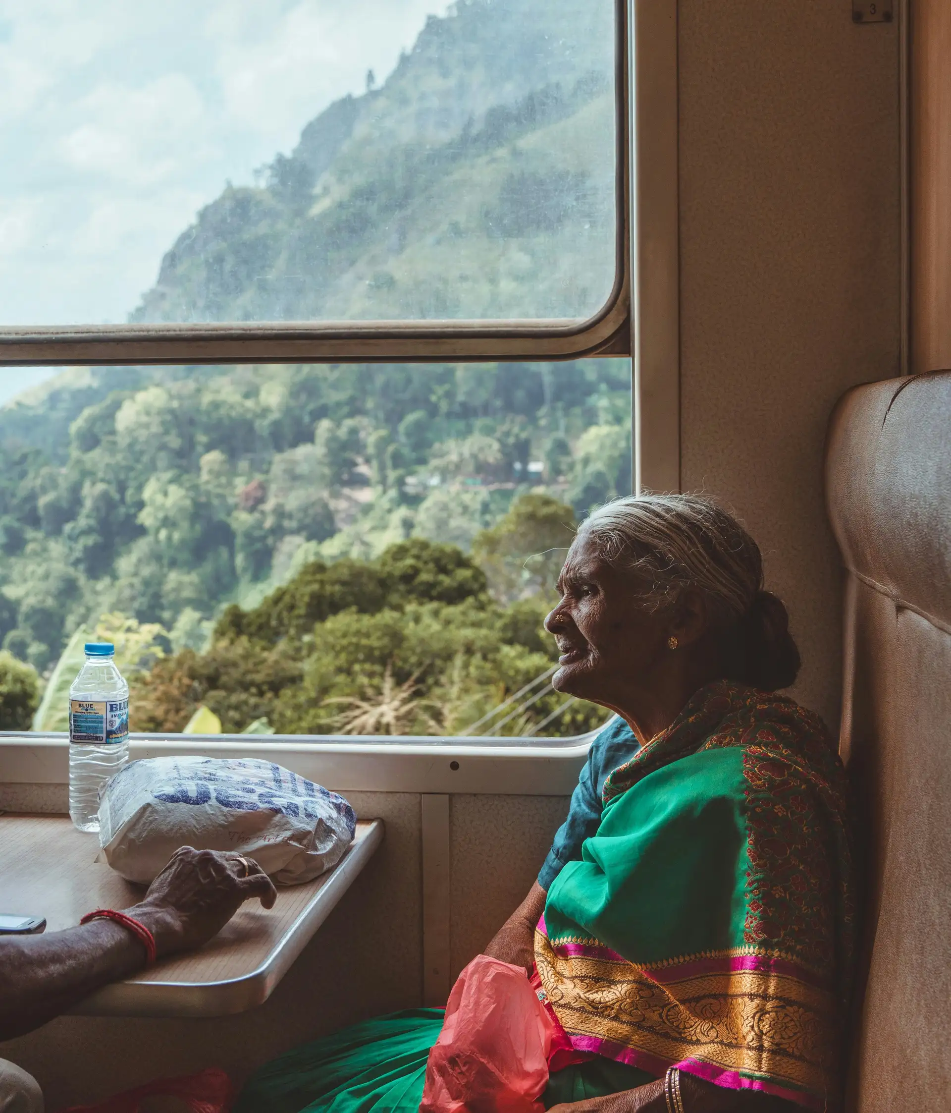 Travel in Asia - An elderly woman wearing a traditional sari sitting in a window seat on a train in Sri Lanka