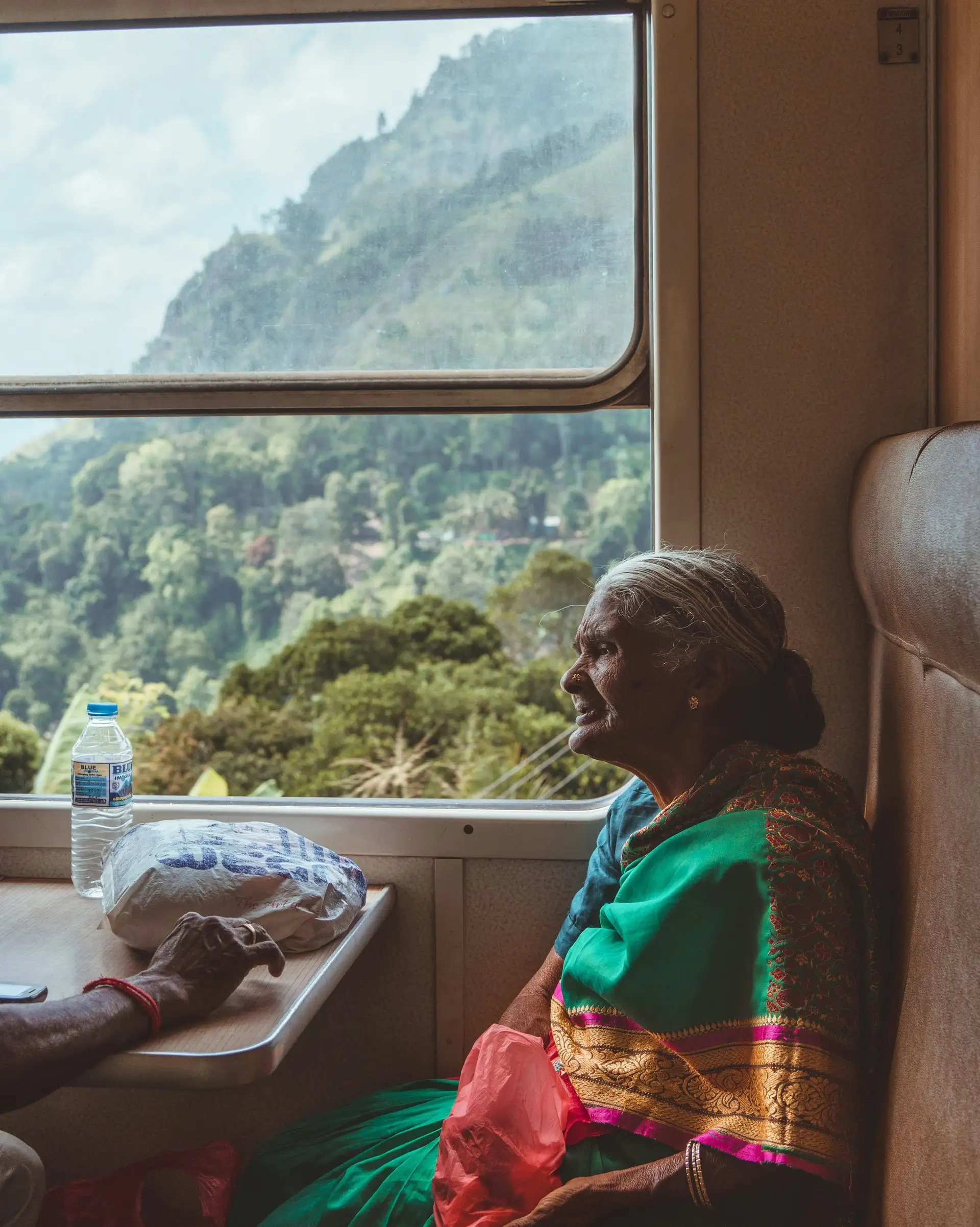 Travel in Asia - An elderly woman wearing a traditional sari sitting in a window seat on a train in Sri Lanka