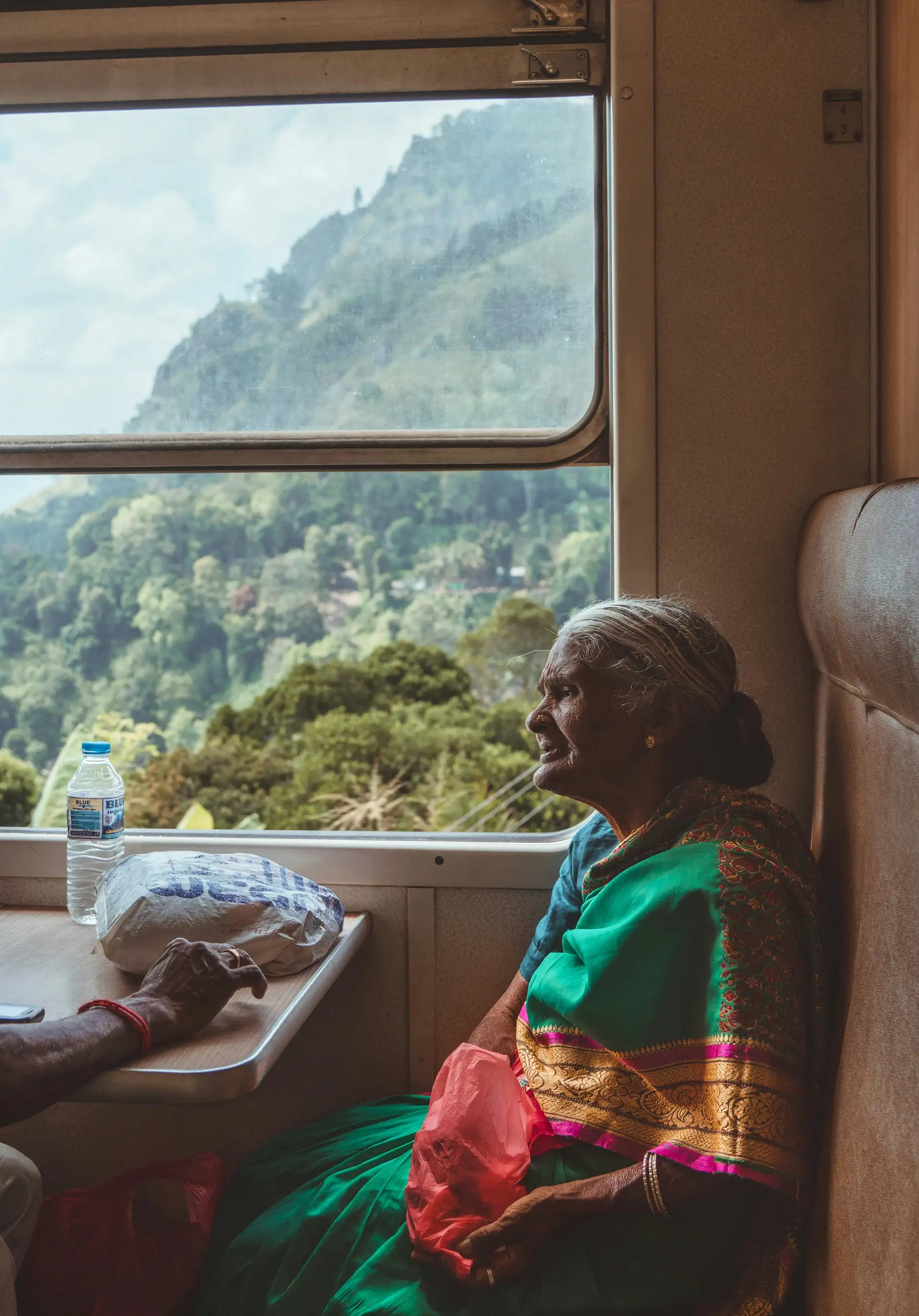 Travel in Asia - An elderly woman wearing a traditional sari sitting in a window seat on a train in Sri Lanka