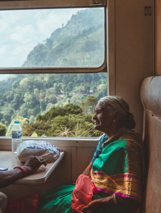 Travel in Asia - An elderly woman wearing a traditional sari sitting in a window seat on a train in Sri Lanka