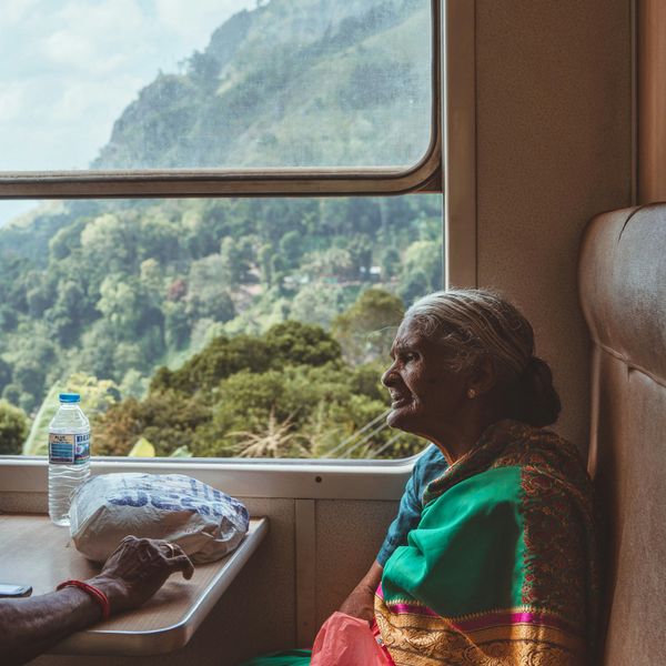 Travel in Asia - An elderly woman wearing a traditional sari sitting in a window seat on a train in Sri Lanka