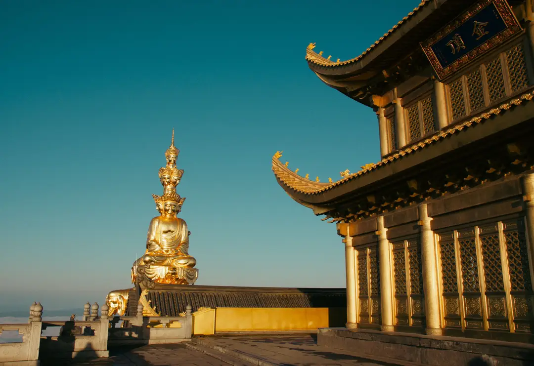 Statue de Bouddha doré et temple sous un ciel bleu clair au mont Emei, Chine.