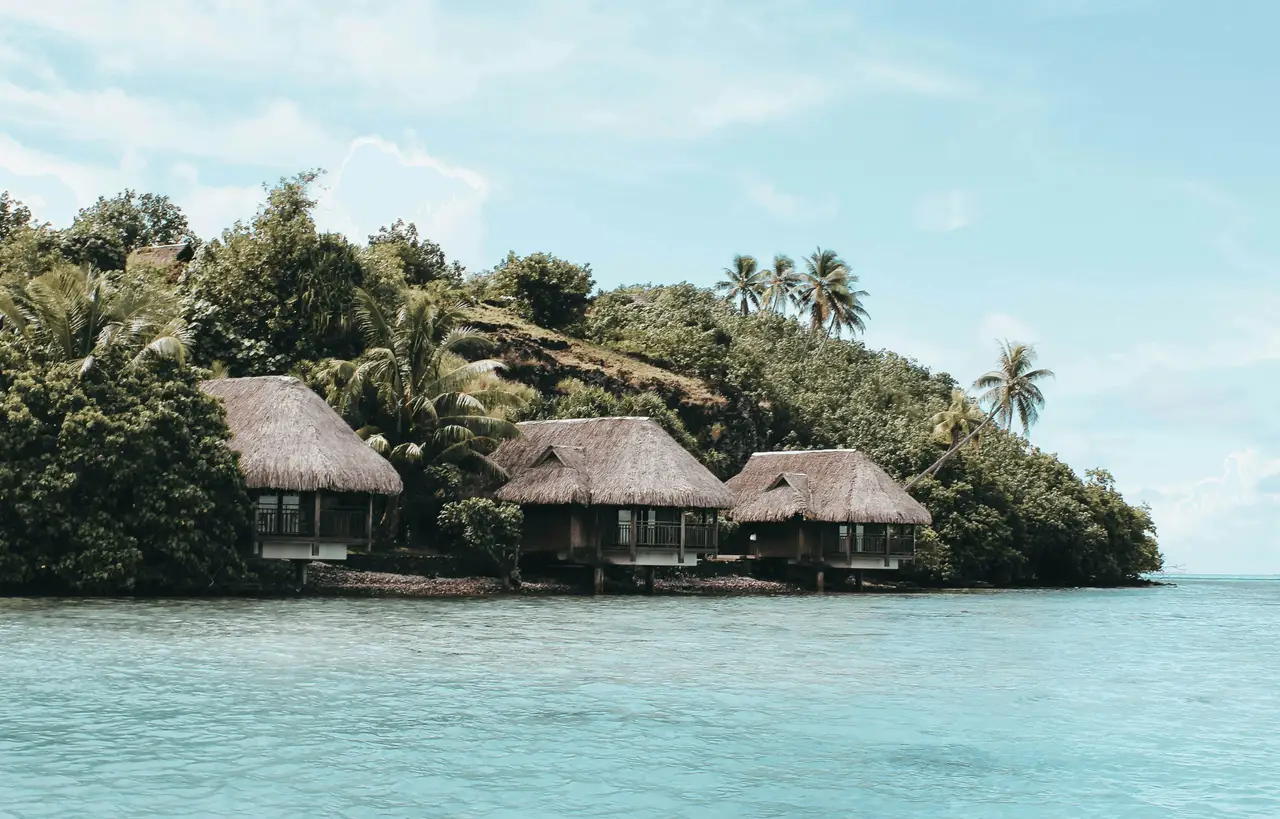 bungalows traditionnels en bois avec toit de chaume au bord d une colline verdoyante face au lagon de bora bora en polynesie francaise