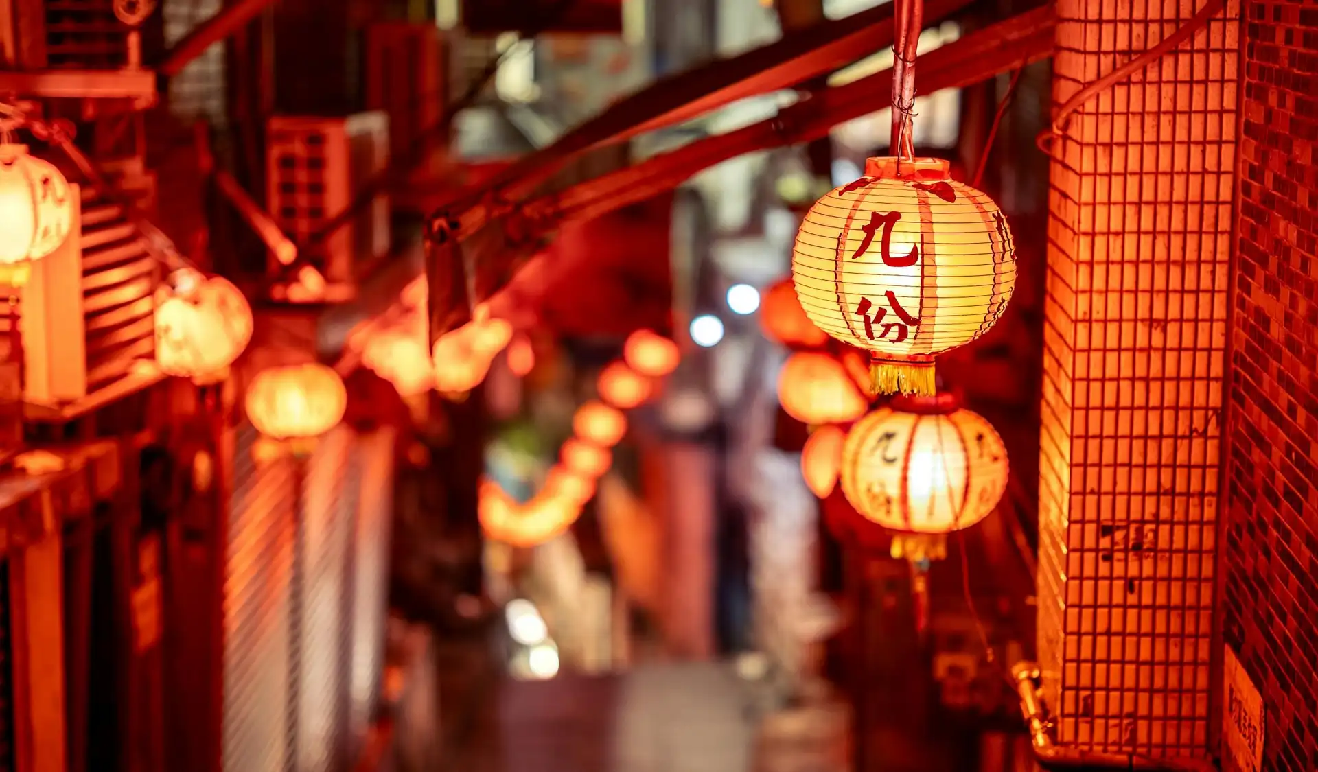 Alignement de lanternes chinoises traditionnelles allumées et suspendues dans une ruelle étroite et animée de la vieille ville de Jiufen à Taïwan.