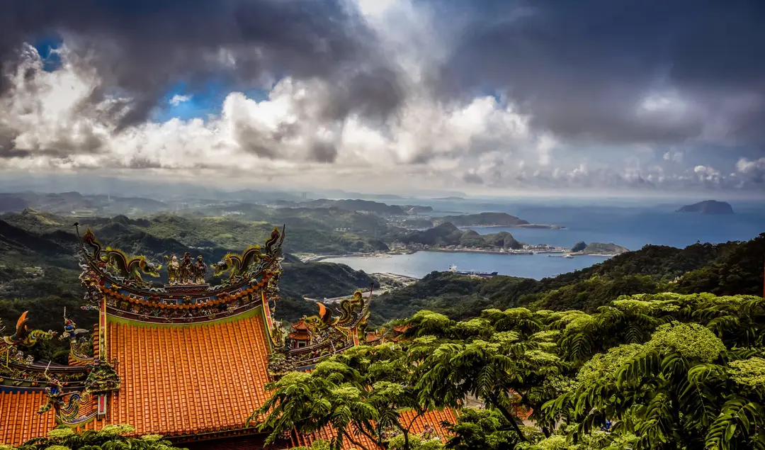 Temple traditionnel surplombant l'océan et un paysage luxuriant sous un ciel nuageux..jpg
