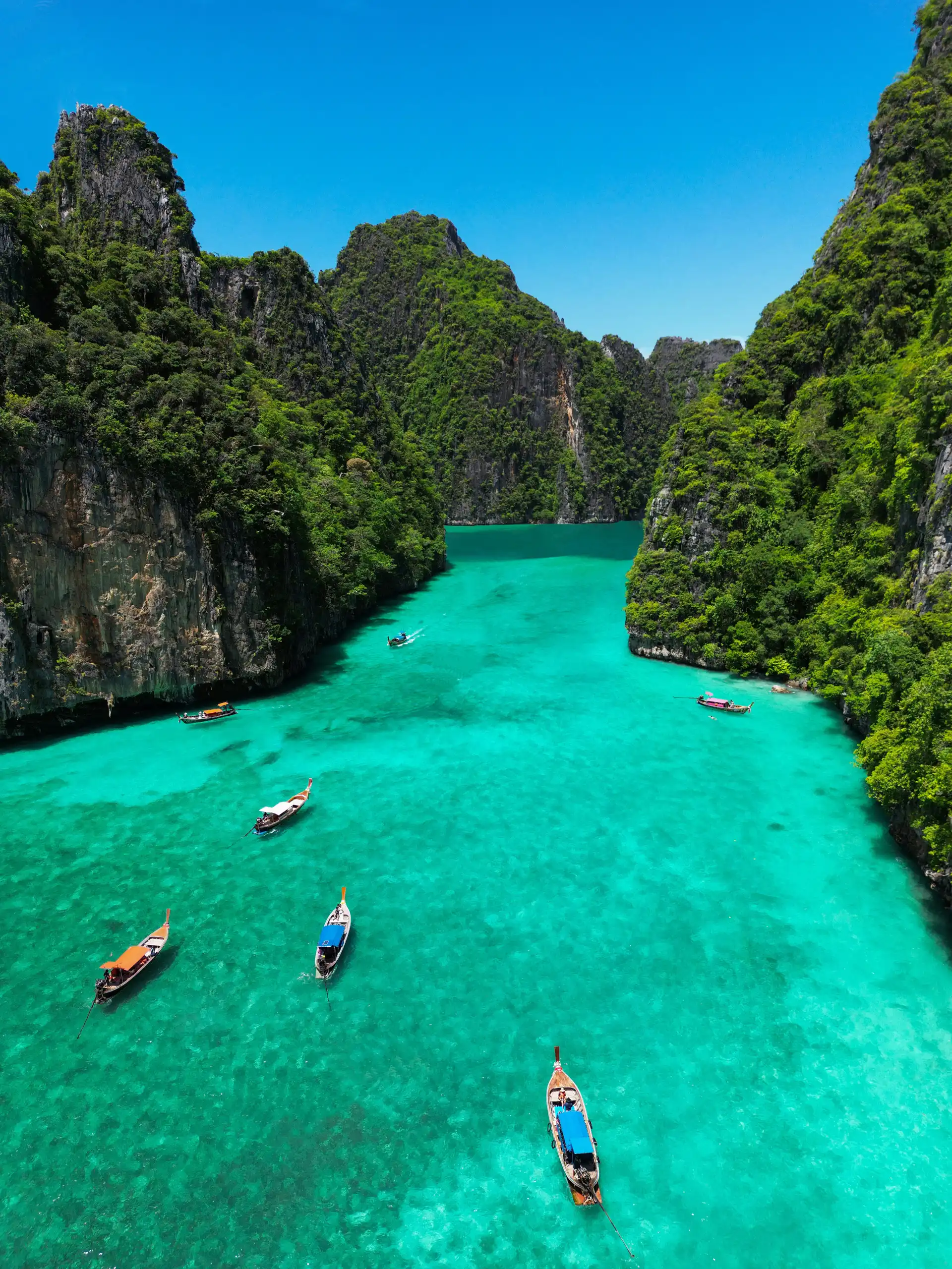 Vue aérienne d'un lagon d'eau turquoise transparente entouré de hautes falaises rocheuses recouvertes de végétation tropicale à Krabi en Thaïlande.