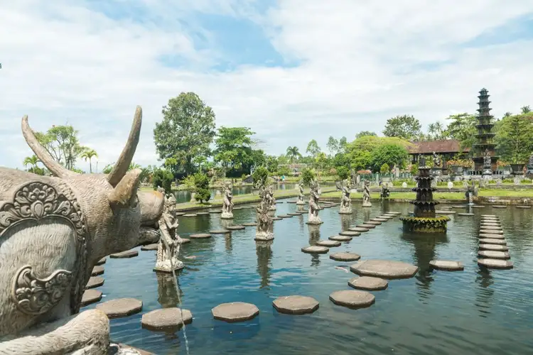 Voyage en Asie — Bassin et statues du palais aquatique Tirta Gangga à Bali : lumière vive et végétation tropicale luxuriante.