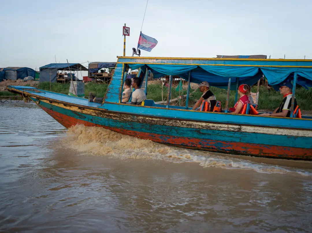 Un bateau à moteur coloré transportant des gens à travers un paysage rural cambodgien