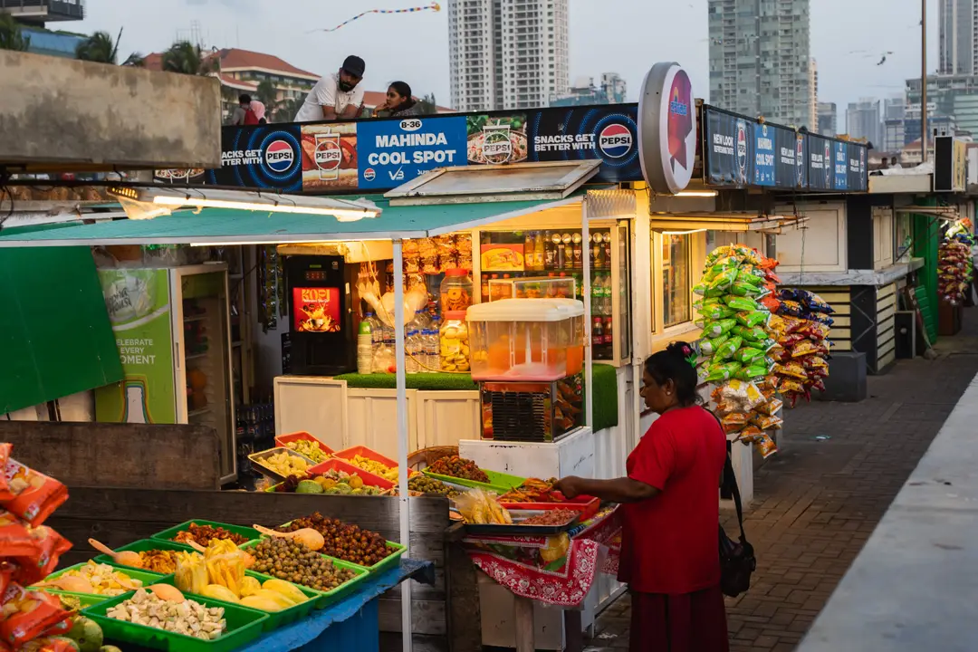 Un étal de marché animé à Colombo, au Sri Lanka, présentant des produits frais et des en-cas au crépuscule.