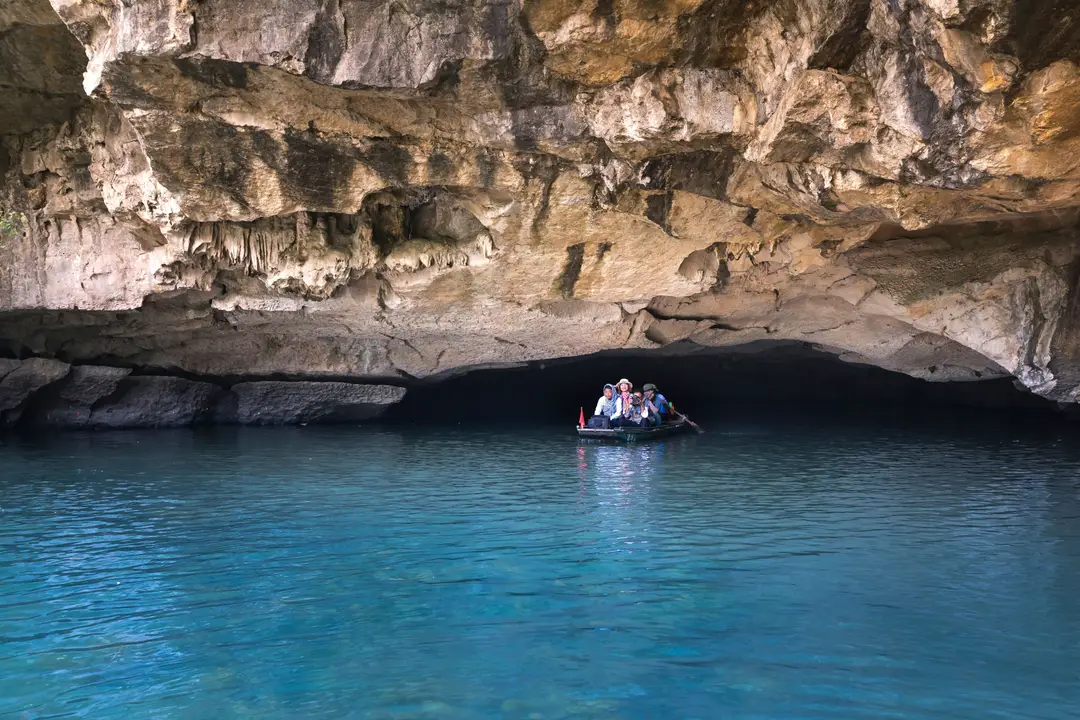 Des visiteurs explorent une grotte en bateau, au milieu de formations calcaires.