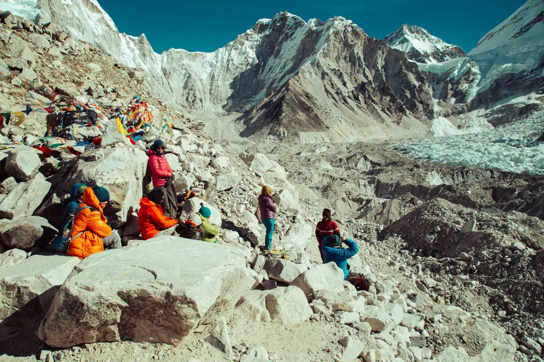 Un groupe de randonneurs se repose au camp de base de l'Everest, entouré de drapeaux de prière et de sommets enneigés de l'Himalaya.jpg