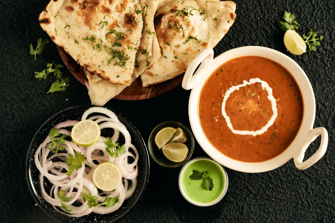 Un repas indien appétissant avec naan, curry crémeux et condiments frais.jpg
