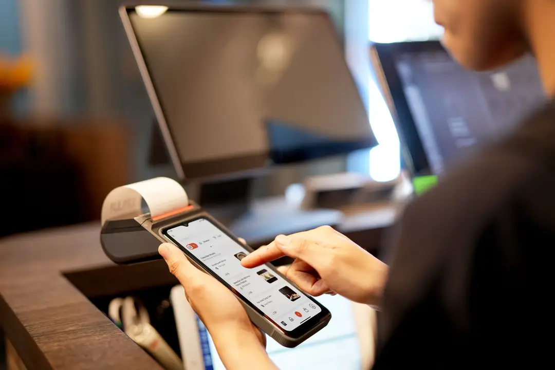 Une personne utilisant un smartphone pour un paiement à un terminal de point de vente moderne à l'intérieur