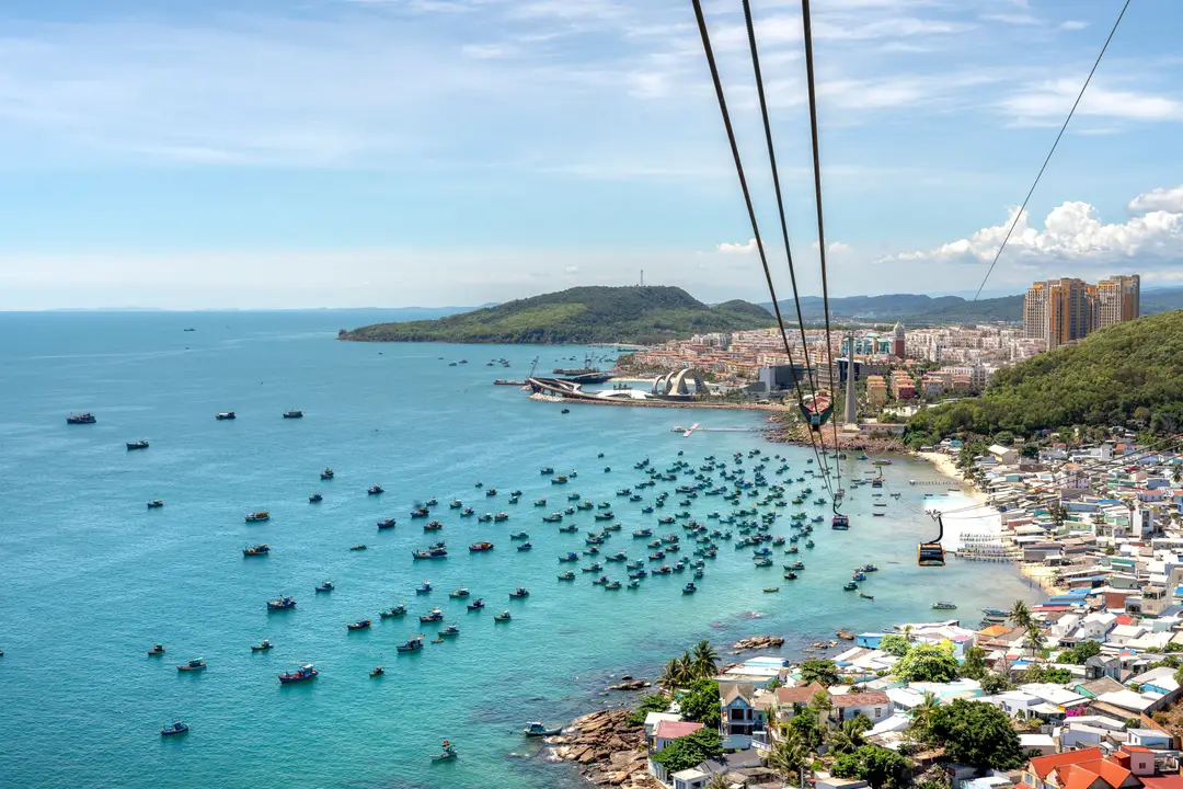 Une vue aérienne époustouflante de l'île de Phu Quoc avec des bateaux, une côte et un téléphérique au-dessus de l'eau bleue