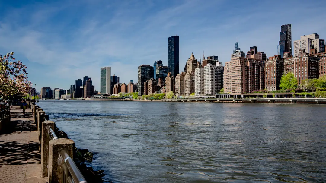 Une vue dynamique de l'horizon de Midtown Manhattan avec une promenade au bord de l'eau par une journée ensoleillée