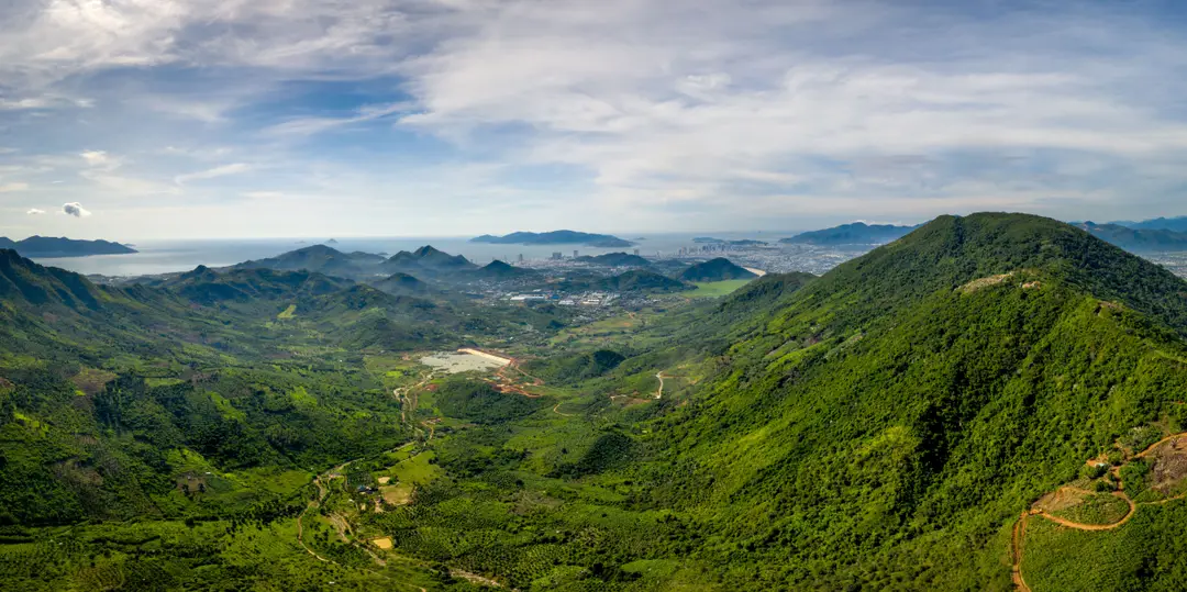 Vue aérienne de Da Nang, de ses montagnes verdoyantes et de son littoral sous un ciel dégagé.