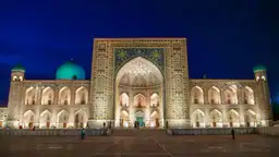 La place du Régistan illuminée de nuit à Samarcande avec la médersa Tilla-Kari et ses minarets.
