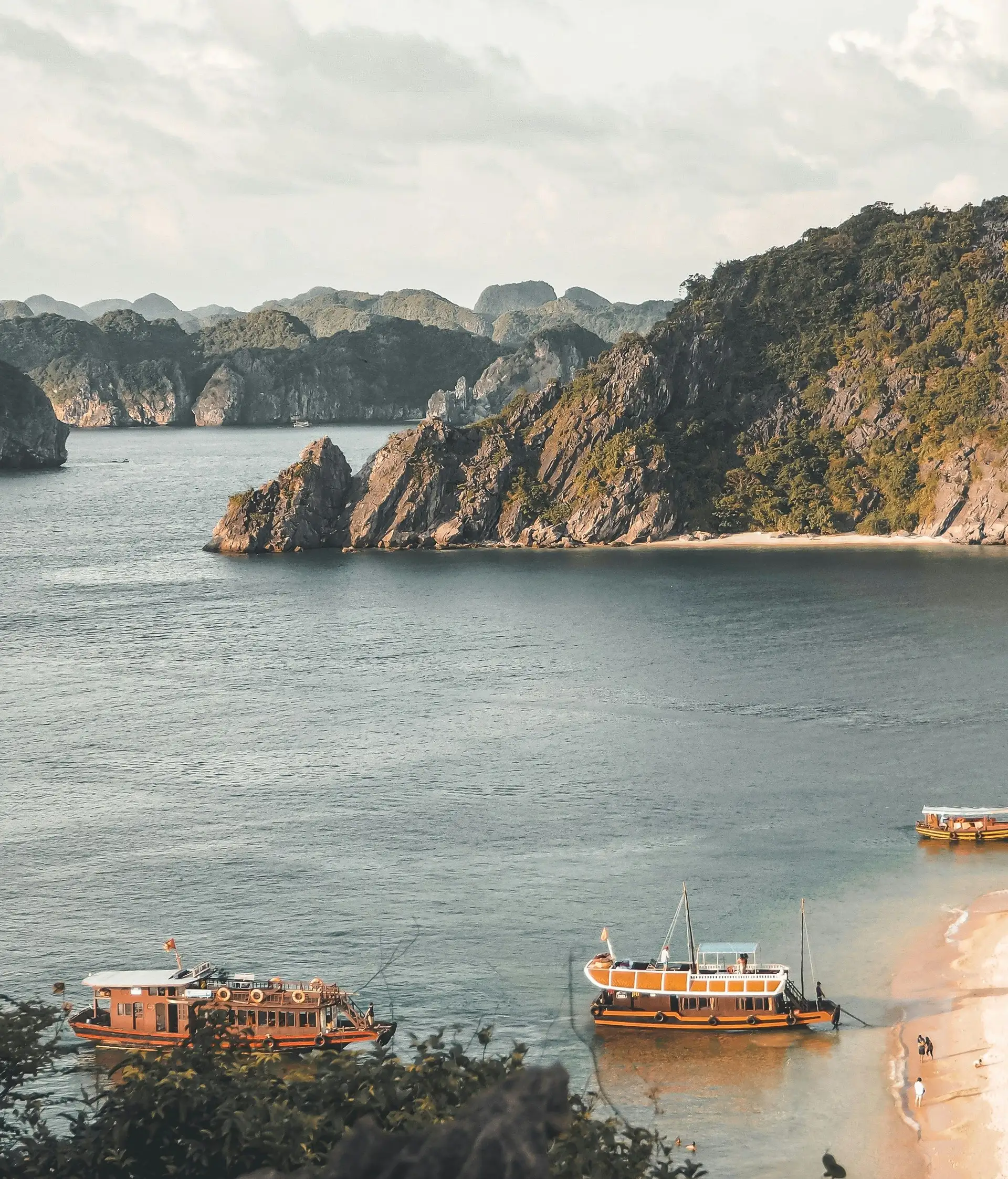 Voyage au Vietnam — Vue panoramique de la Baie d’Ha Long avec ses îlots karstiques et des bateaux traditionnels dans une eau calme.