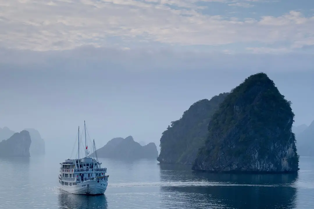 Voyage en Asie – Bateau de croisière traditionnel naviguant au calme entre les pains de sucre de la baie d'Halong au Vietnam.