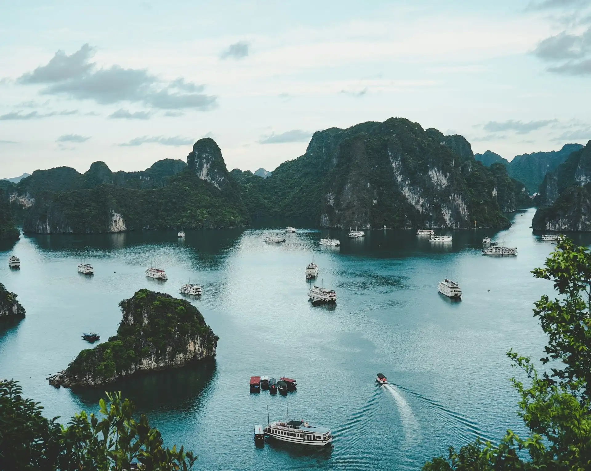 Vue panoramique sur les majestueux pitons rocheux et îles de calcaire de la baie d'Halong parsemée de bateaux de croisière au Vietnam.