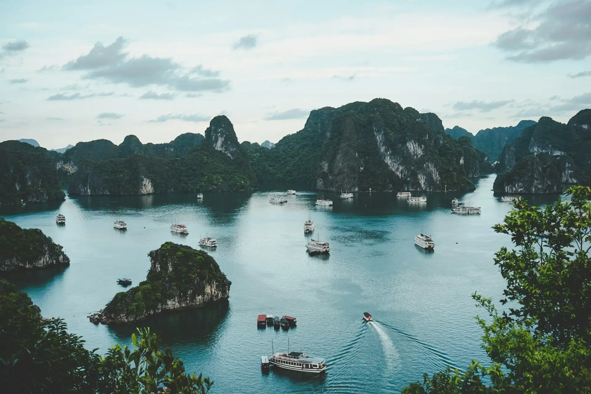 Vue panoramique sur les majestueux pitons rocheux et îles de calcaire de la baie d'Halong parsemée de bateaux de croisière au Vietnam.