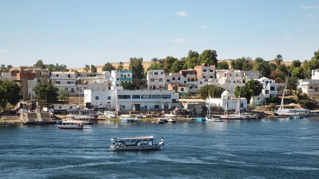Rive d’Assouan avec des bateaux traditionnels et des maisons au bord du Nil
