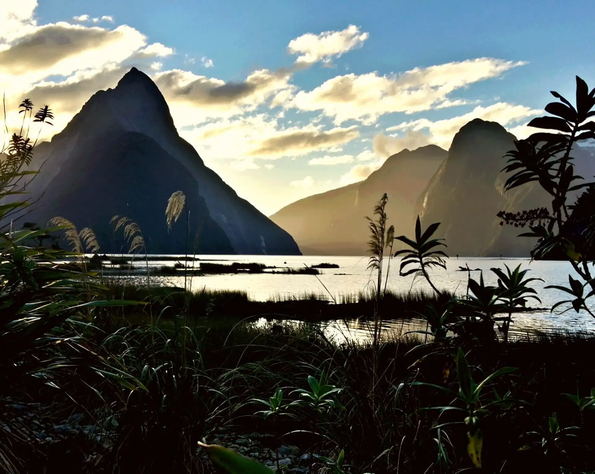 Vue crépusculaire sur le fjord de Milford Sound et la montagne Mitre Peak se reflétant dans les eaux calmes en Nouvelle-Zélande.