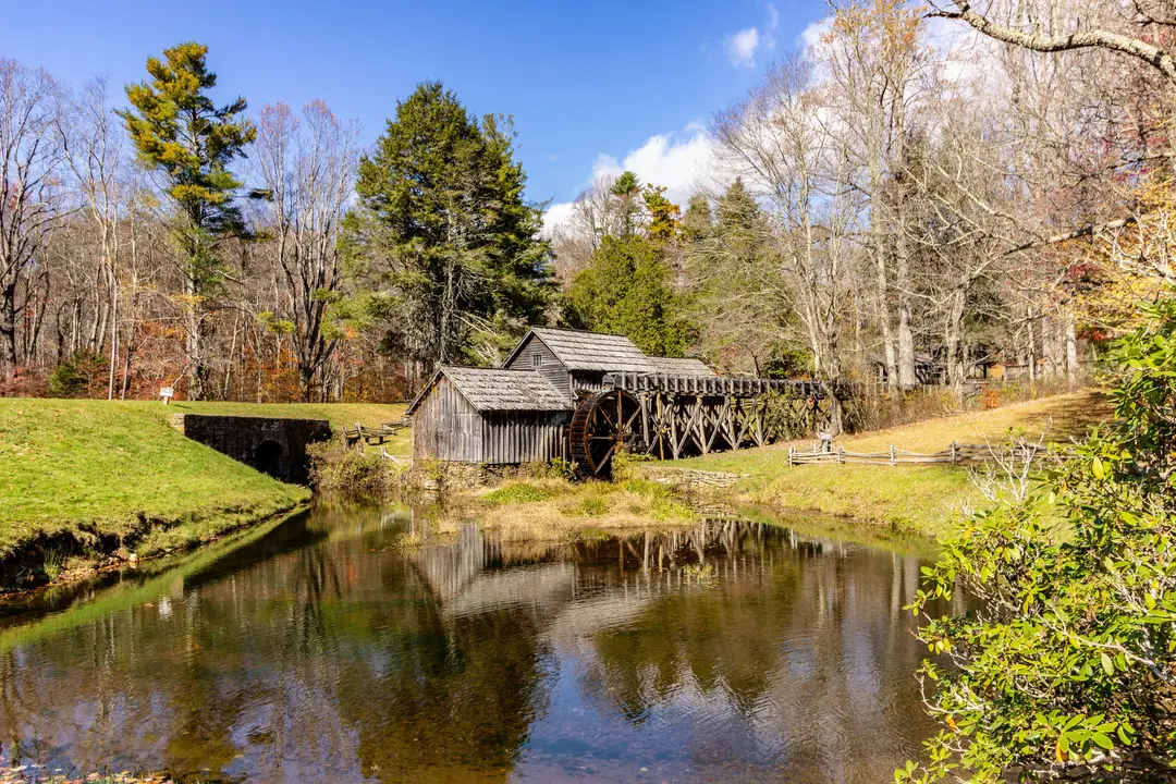 Le moulin historique de Mabry Mill se reflète dans un étang bordé d’arbres aux couleurs automnales.