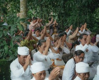 balinesische Menschen sitzen in weißer Kleidung und beten