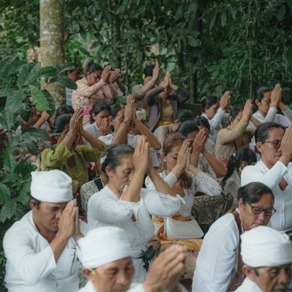 balinesische Menschen sitzen in weißer Kleidung und beten