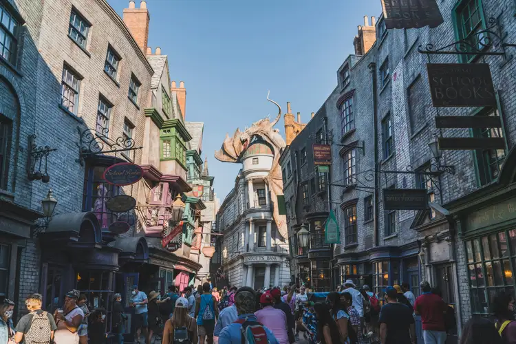 Ruelle pavée animée du Chemin de Traverse dominée par un dragon perché sur un toit dans un parc d'attractions à Orlando