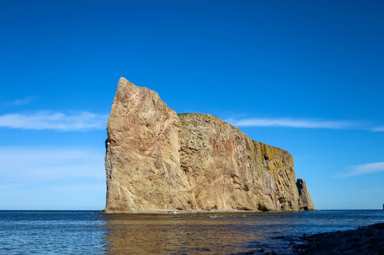 Imposante falaise calcaire du Rocher Percé émergeant des eaux bleues du golfe du Saint-Laurent sous un ciel dégagé en Gaspésie