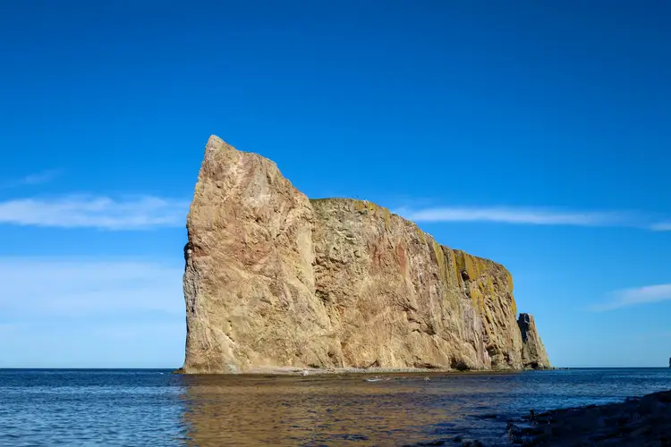 Imposante falaise calcaire du Rocher Percé émergeant des eaux bleues du golfe du Saint-Laurent sous un ciel dégagé en Gaspésie