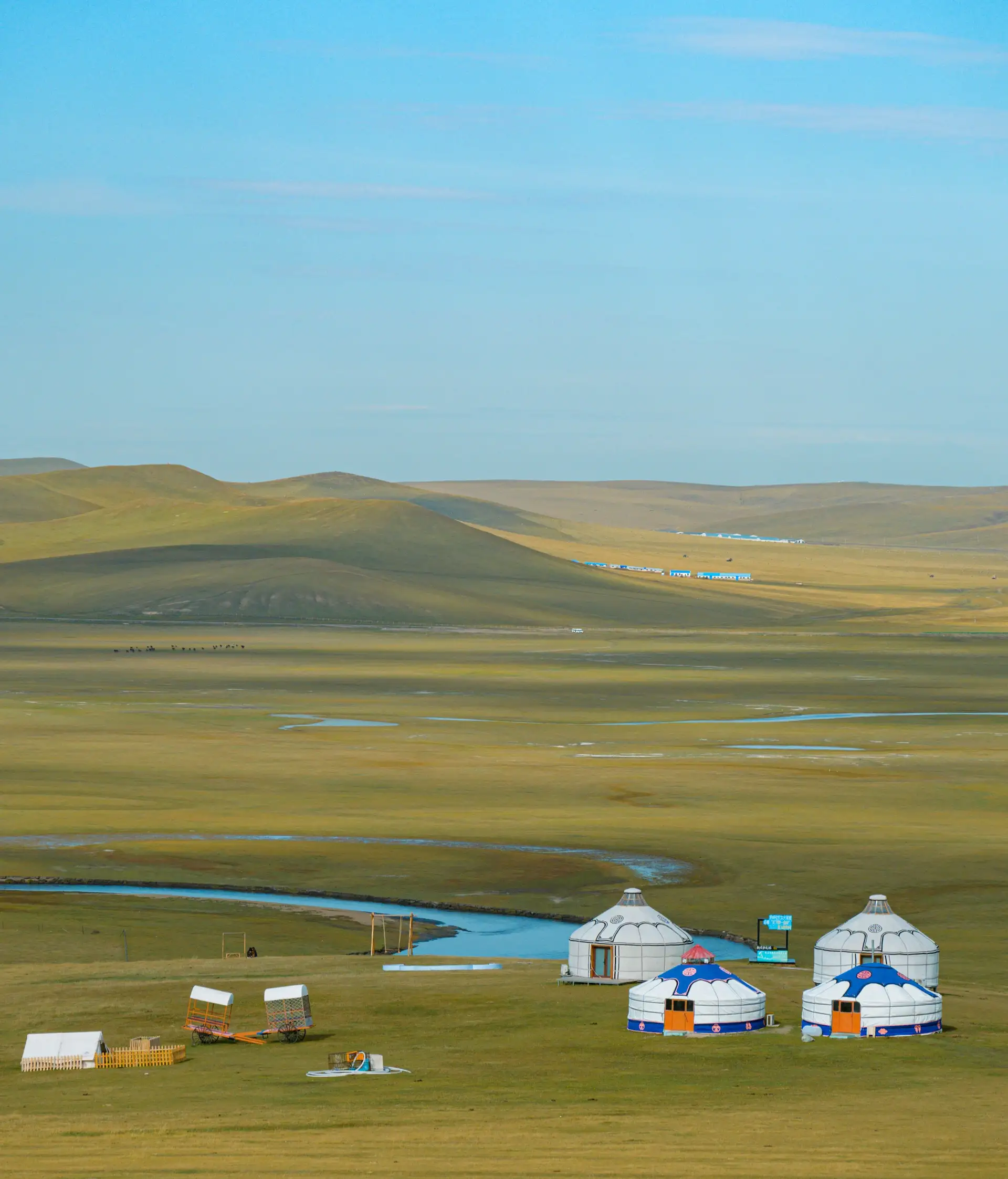 Quatre yourtes blanches sur une vaste plaine herbeuse en Mongolie