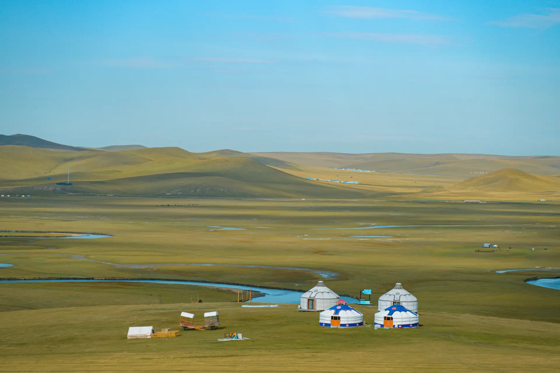Quatre yourtes blanches sur une vaste plaine herbeuse en Mongolie
