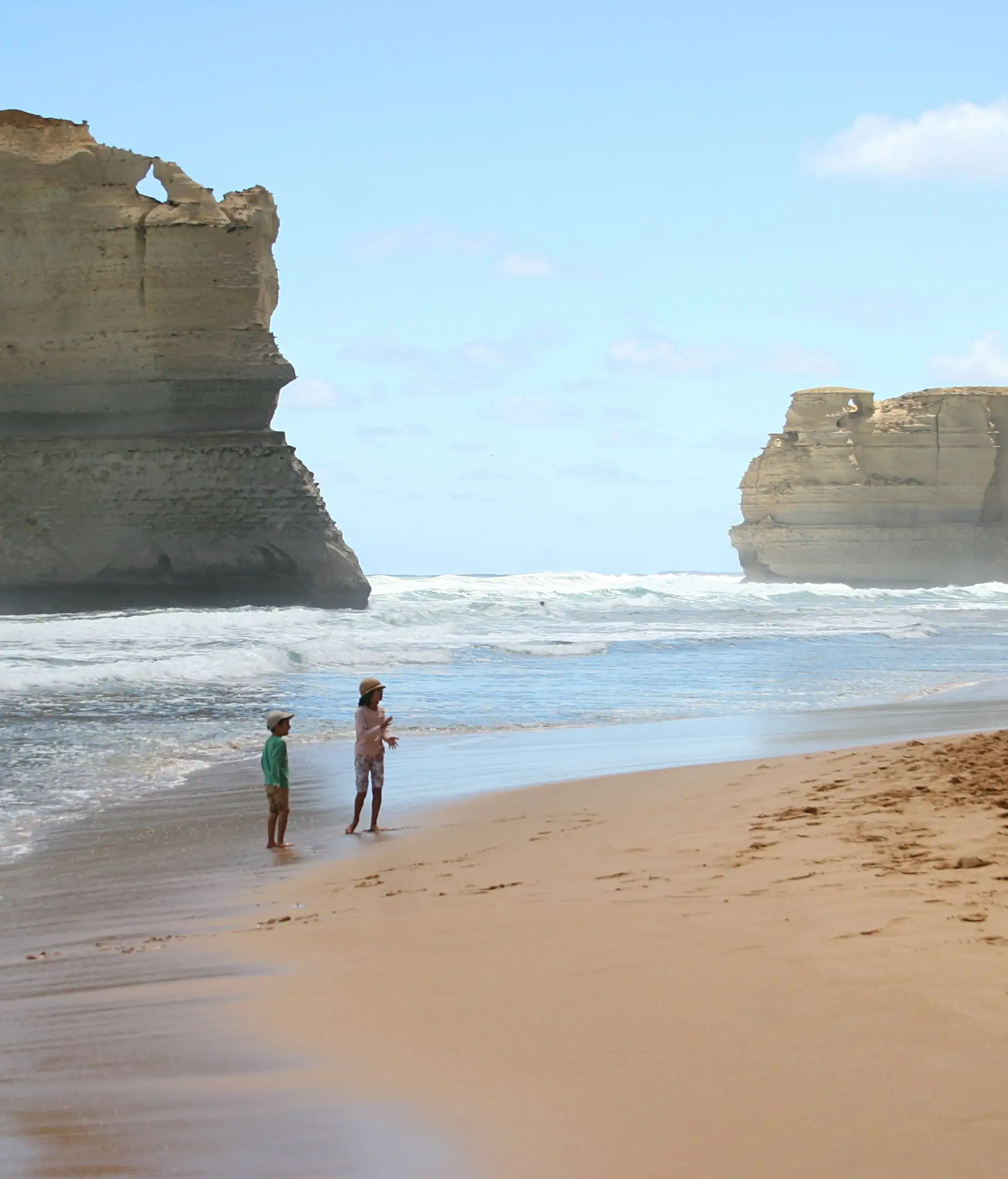 Enfants jouant sur la plage devant les falaises des Douze Apôtres