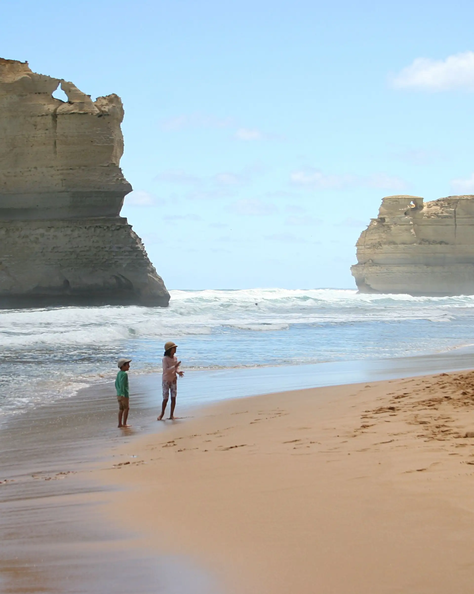 Enfants jouant sur la plage devant les falaises des Douze Apôtres
