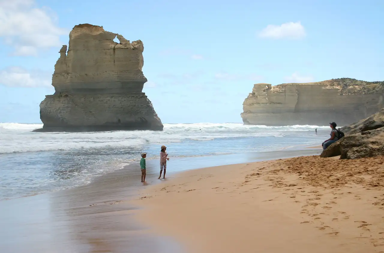 Enfants jouant sur la plage devant les falaises des Douze Apôtres