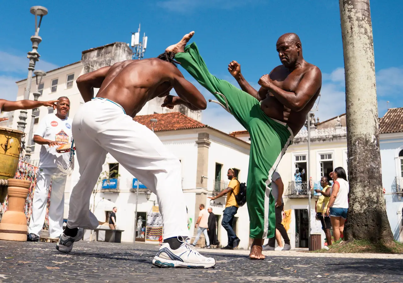 Voyage au Brésil – Deux hommes pratiquant la capoeira lors d'une démonstration de cet art martial traditionnel afro-brésilien sur une place de Salvador de Bahia.