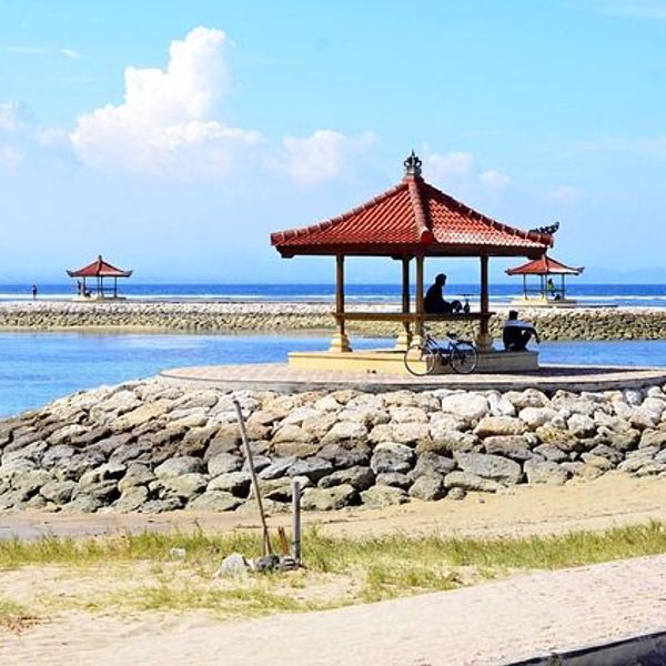 Voyage en Asie — Plage à Bali avec gazebos sur plates-formes en pierre : eau bleu vif et ciel ensoleillé.