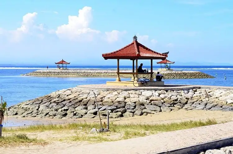 Voyage en Asie — Plage à Bali avec gazebos sur plates-formes en pierre : eau bleu vif et ciel ensoleillé.