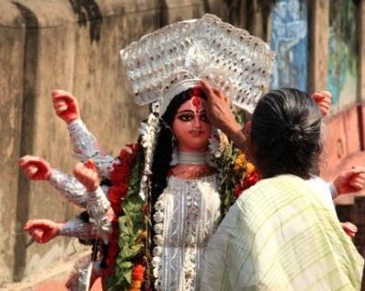 Travel in Asia - A woman applying a sindoor to the forehead of a statue at the Durga Puja festival in India