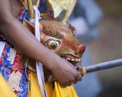 Travel in Asia - A child holding a traditional mask used in a tshechu festival in Bhutan