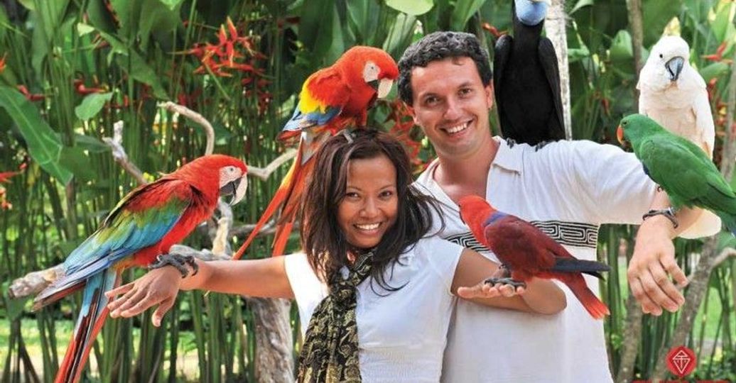 Voyage en Asie - couple en voyage de noces à Bali entouré de perroquets tropicaux dans un jardin exotique