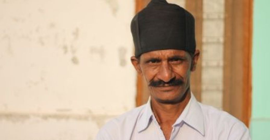 Travel in Asia - A man with a thick mustache and a black hat looking into the camera