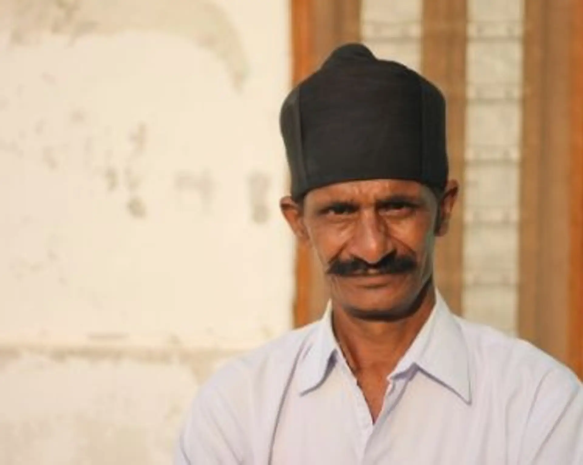 Travel in Asia - A man with a thick mustache and a black hat looking into the camera