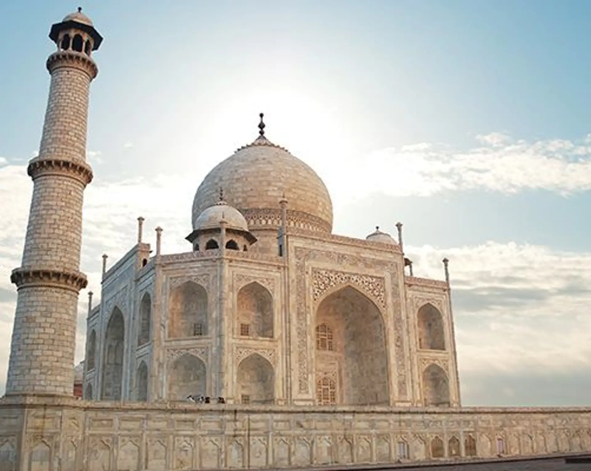 Voyage en Asie — Taj Mahal à Agra en Inde, mausolée de marbre blanc emblématique entouré de ses minarets sous un ciel clair.